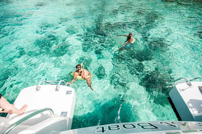 Catamaran sailing toward St. John USVI with guests snorkeling in crystal-clear Caribbean water on a day trip from St. Thomas
